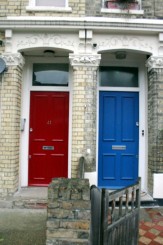 primo piano di due portoncini d'ingresso di due case londinesi: a sinistra il portoncino di colore rosso, a destra di colore blu