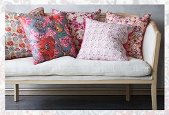 Un divano con cuscini rivestiti con tessuto in stile liberty Intaglio su legno pieno.