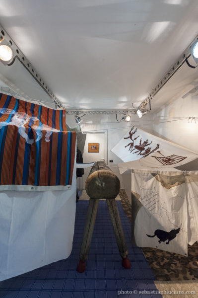Il lavoro di Grossi Maglioni, Polisportiva Casal Bertone Occupata (foto di Sedastiano Luciano) – alt: tende diverse sono appese al muro in una stanza