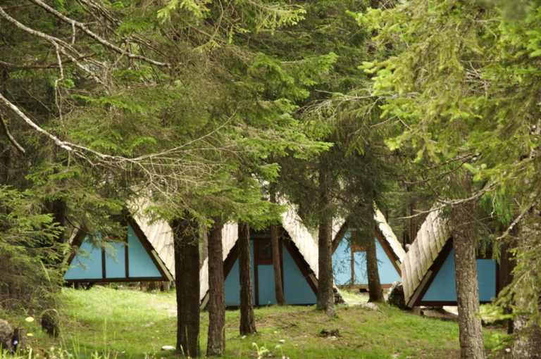 Il camping, Villaggio Eni di Borca di Cadore, foto di Sergio Casagrande- Piccole casupole a forma triangolare immerse nel bosco.