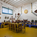 pavimento giallo come anche il tavolo e sedie poste al centro, decorazioni sulla parte alta delle pareti
