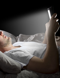 elettromagnetismo in casa: uomo sdraiato sul letto guarda il cellulare